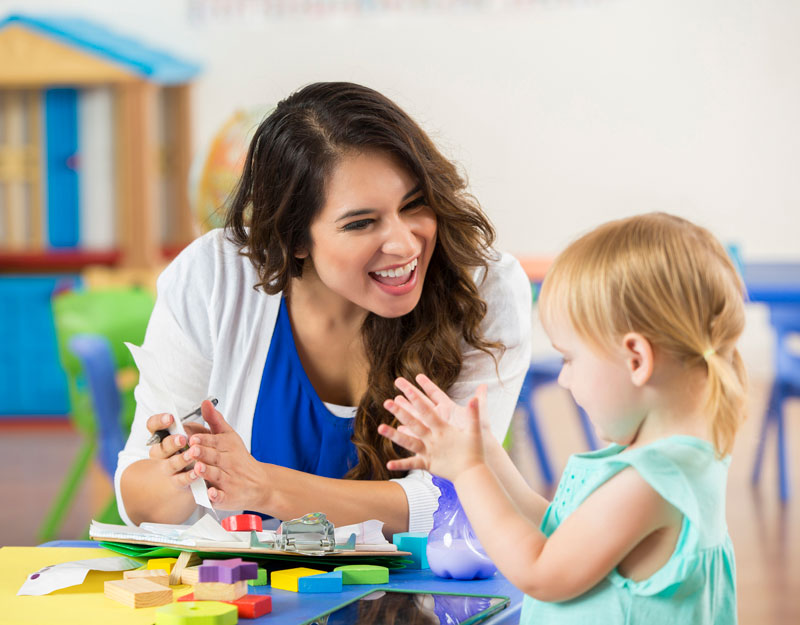 Teacher with a young student playing with toys at daycare