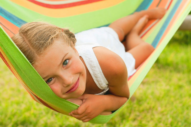 Girl laying outisde in a striped hammock enjoying summer activities