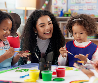 Teacher helping daycare children with their STEAM activity painting project
