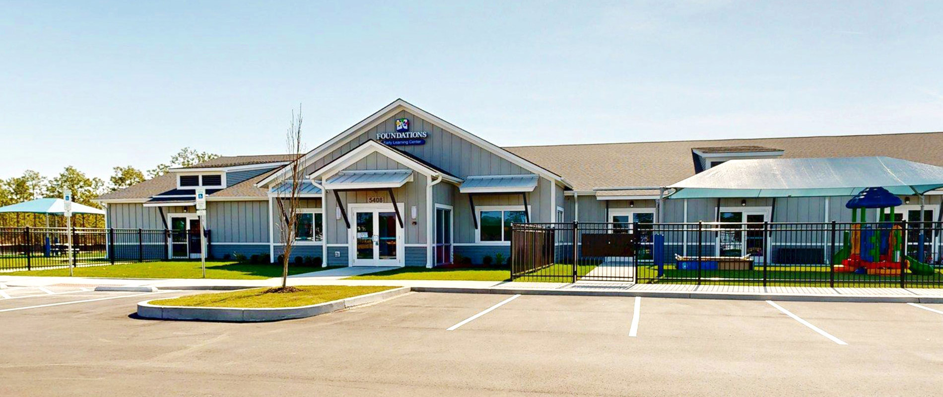Exterior of Foundations Early Learning Center Riverlights, a modern single-story building with board-and-batten siding, prominent entrance, and parking lot