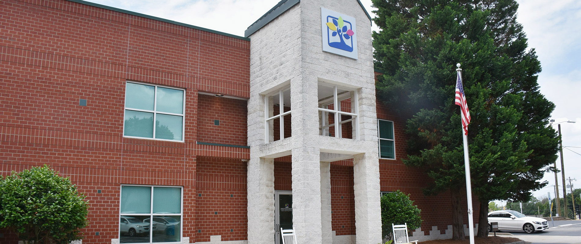 Exterior of Foundations Early Learning Center WS Downtown with red brick building, stone entrance tower with school logo, and American flag