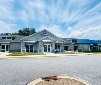 Exterior view of a Foundations Early Learning Center building with covered playground area on a sunny day