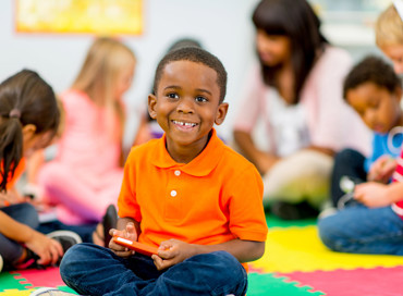 Pre-K child in an orange shirt in daycare classroom