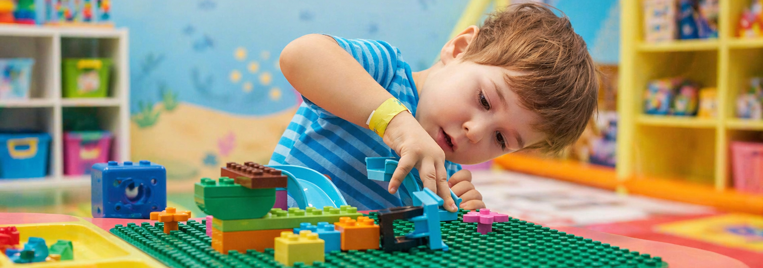 Young boy doing legos at a table in a colorful classroom