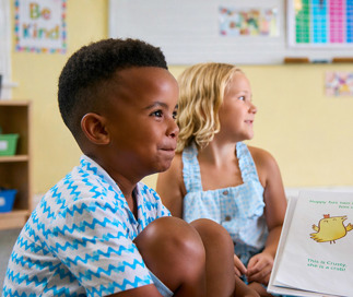 Teacher reading a story book to a group of yound children