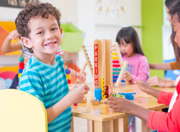 First Steps Pre-K students play with blocks and cars in a daycare classroom.