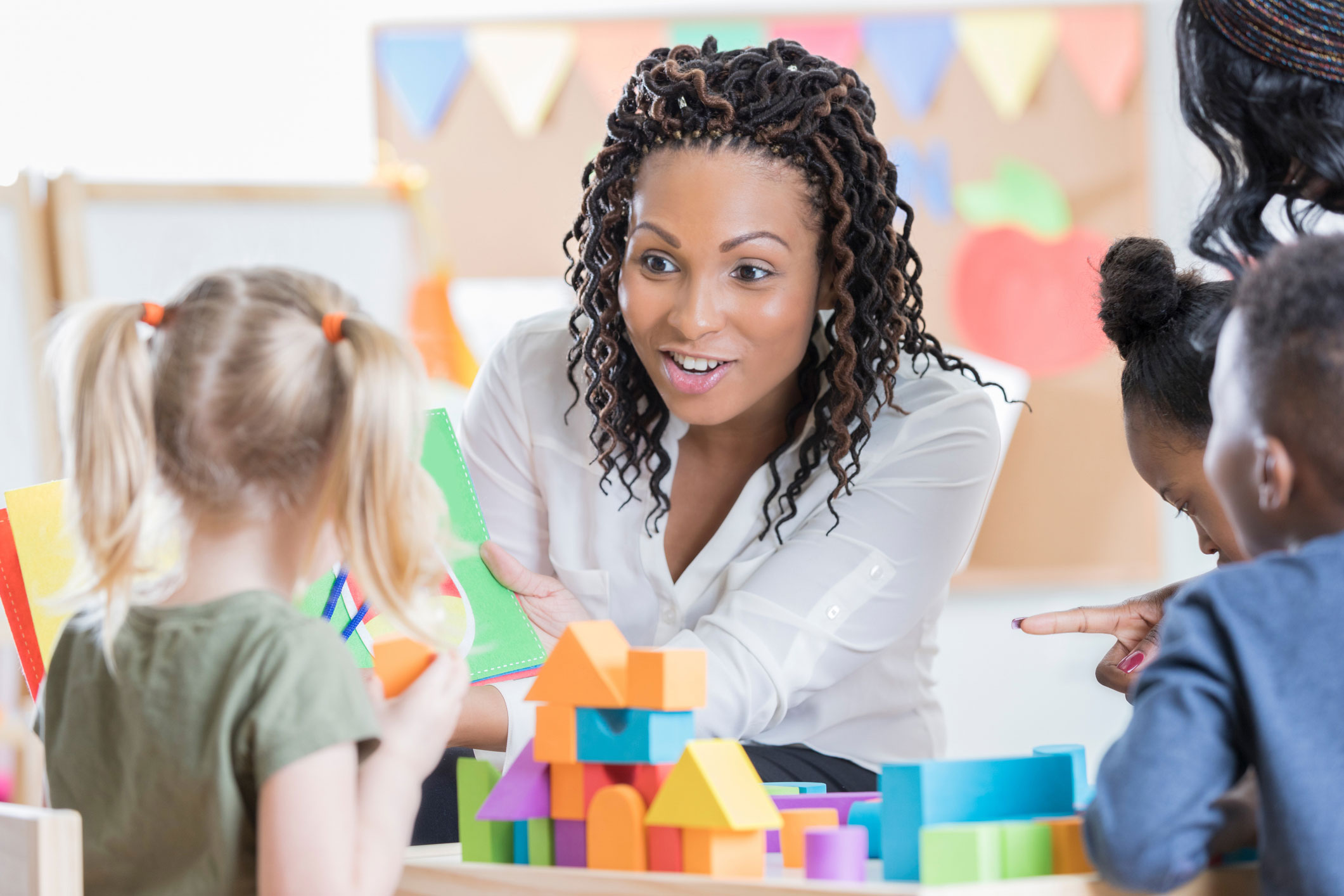 Teacher with a group of young daycare children teaching and playing blocks