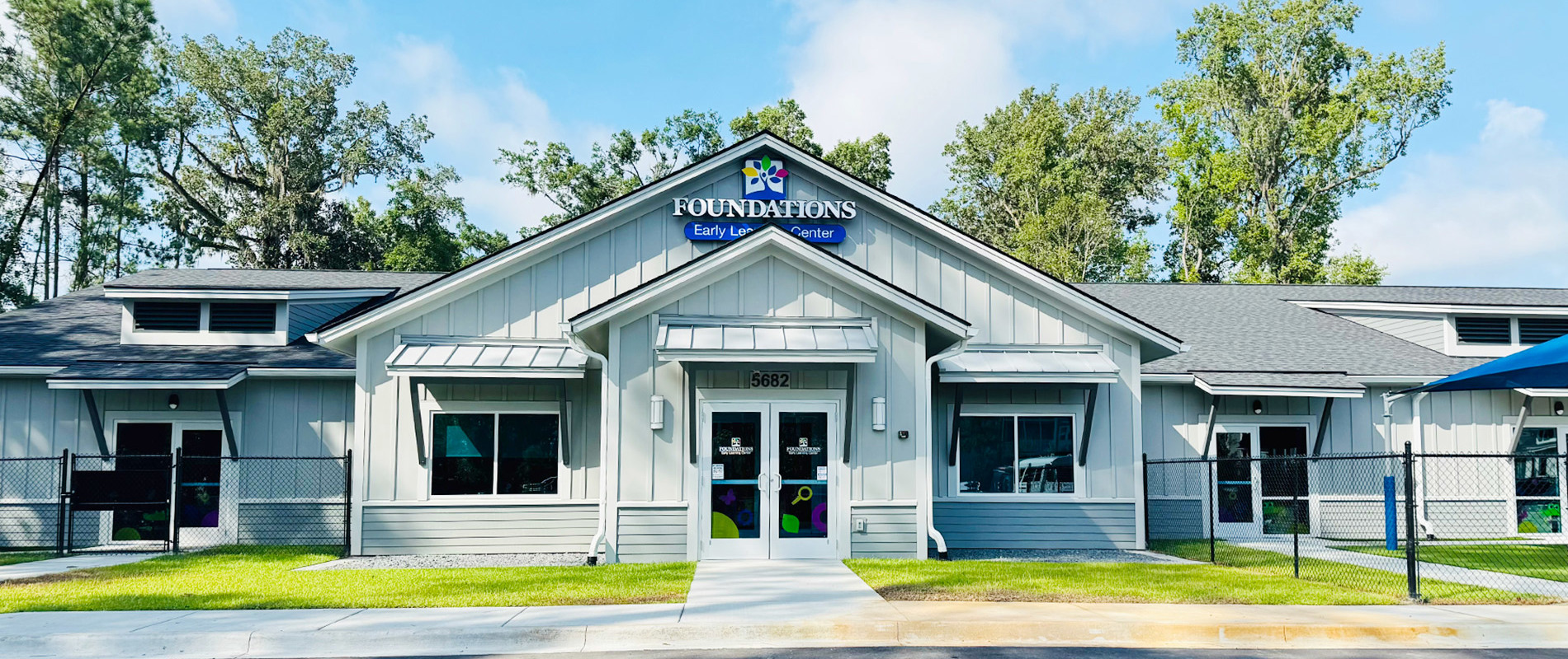 Exterior of Foundations Early Learning Center Savannah, a modern single-story building with board-and-batten siding and gabled entrance surrounded by trees