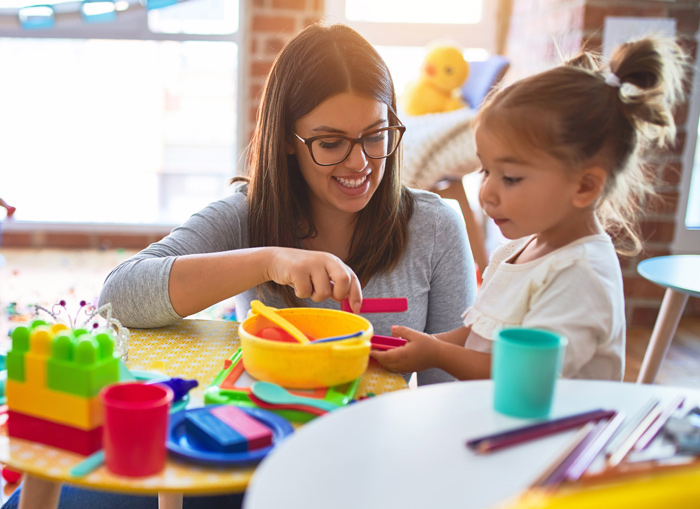 Teacher with early preschool child learning by pretend play