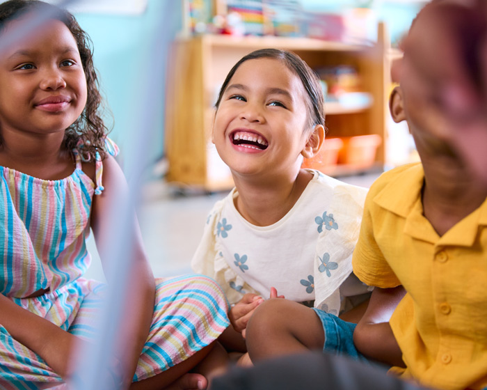 Afterschool students sitting in a group laughing in the classroom.