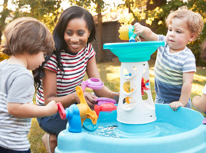 Teacher and children outside playing with a water table