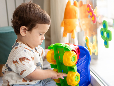 Toddler boy explores and investigates a colorful toy truck