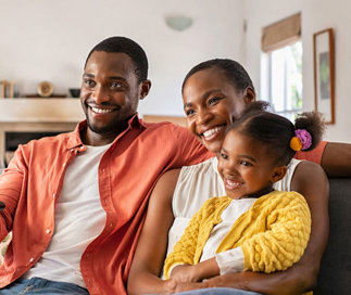 Family sitting at home on couch with their Pre-K Foundations Early Learning Center student