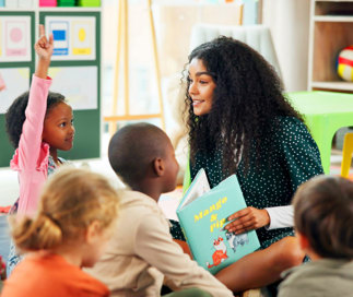 Young teacher reading to a group of engaged children in a classroom