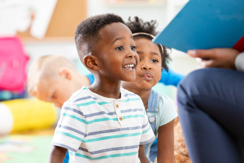 Preschool boy in striped shirt engaged in storytime at daycare