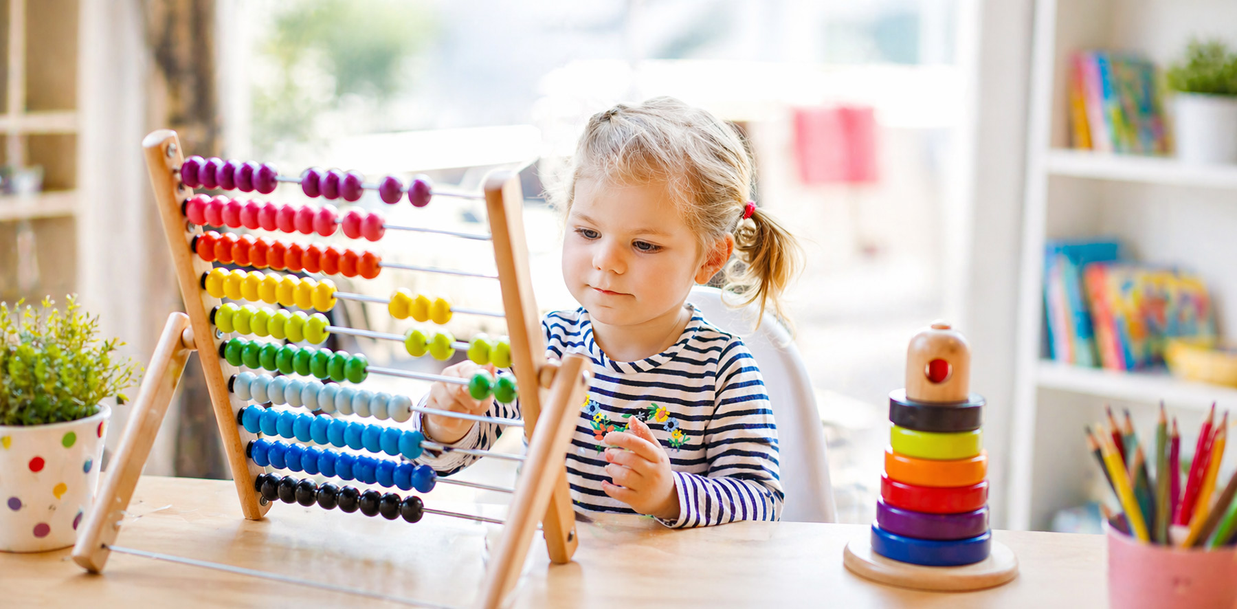 Young girl in daycaren playing with STEAM toys and puzzles at a table