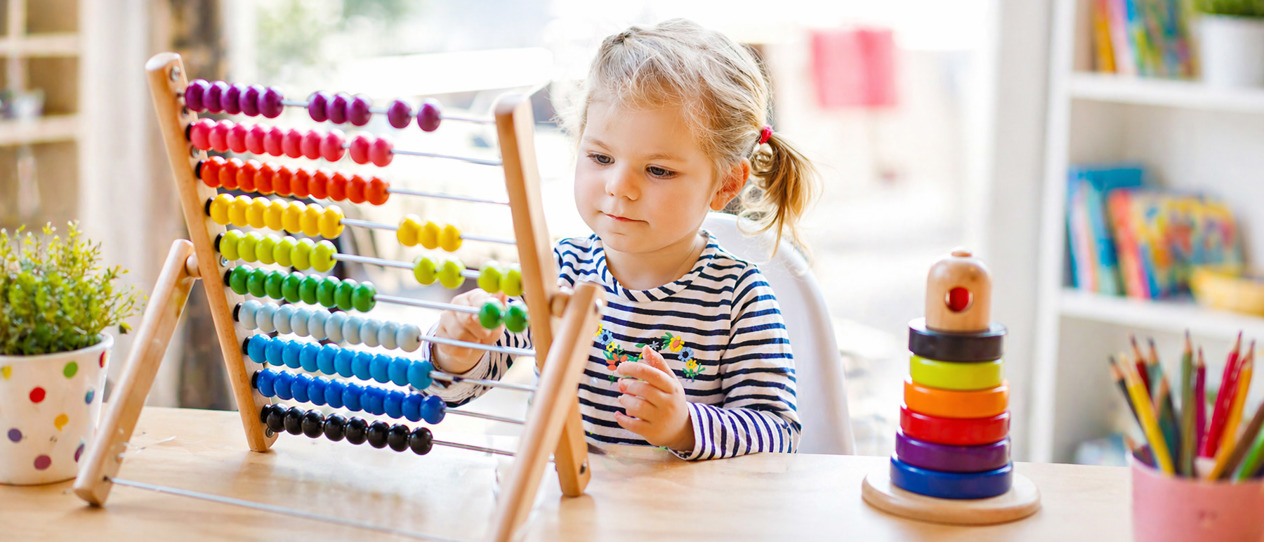 Young girl in daycaren playing with STEAM toys and puzzles at a table