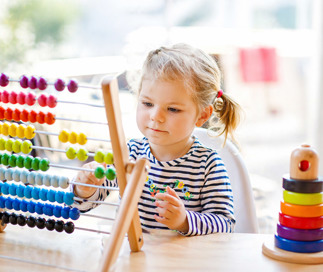 Young girl in daycaren playing with STEAM toys and puzzles at a table