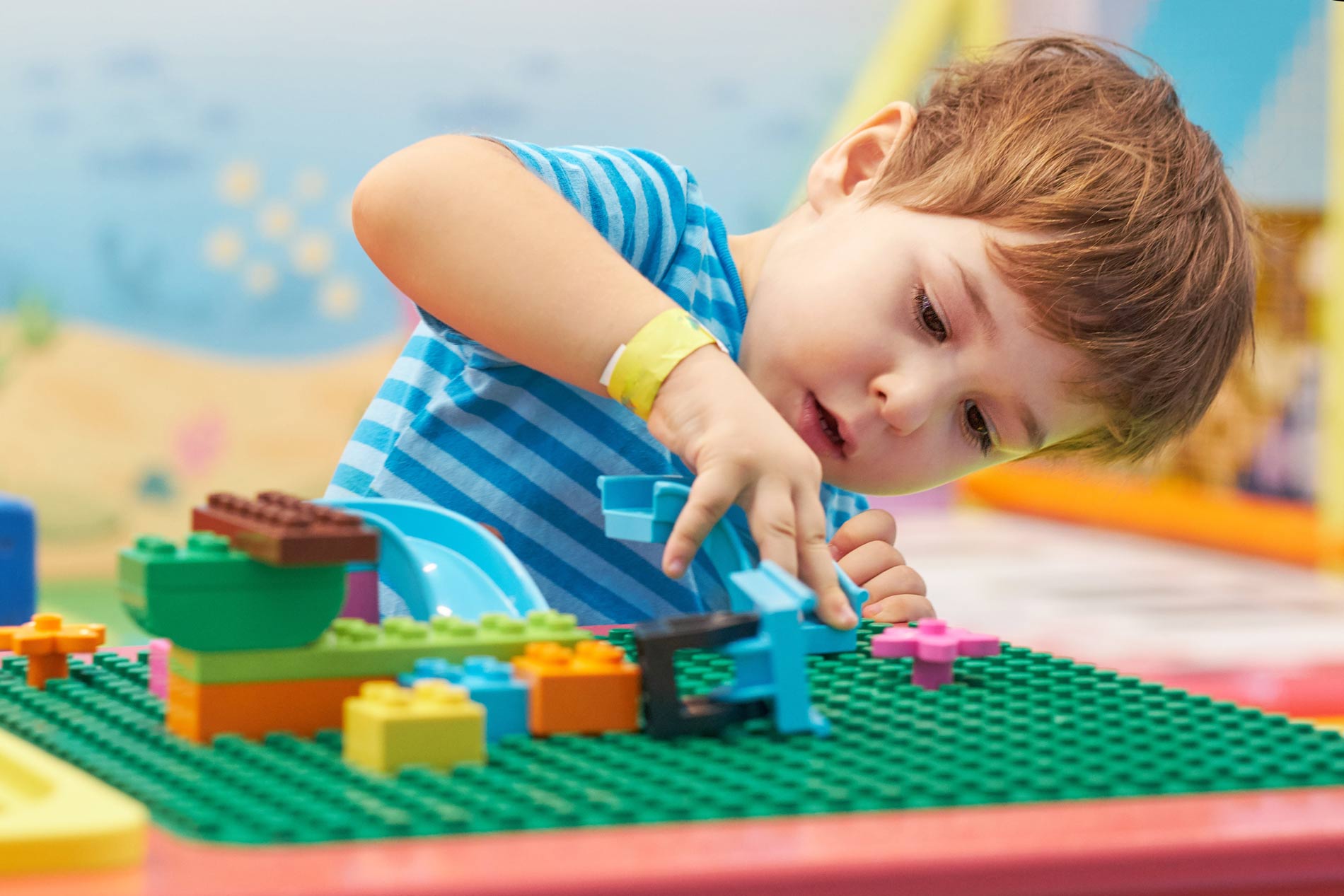 First Steps Pre-K boy plays builds with colorful blocks at a lego table.