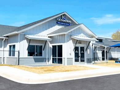 Exterior front view of a Foundations Early Learning Center building with signage and covered entrance on a clear sunny day