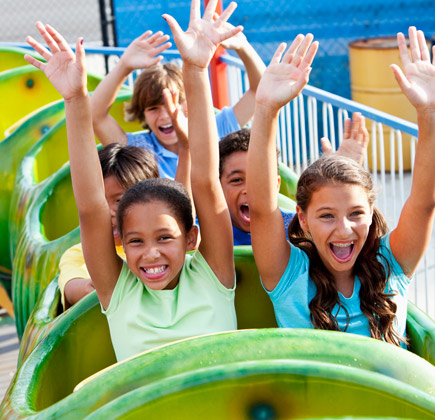happy children riding a roller coaster at amusement park